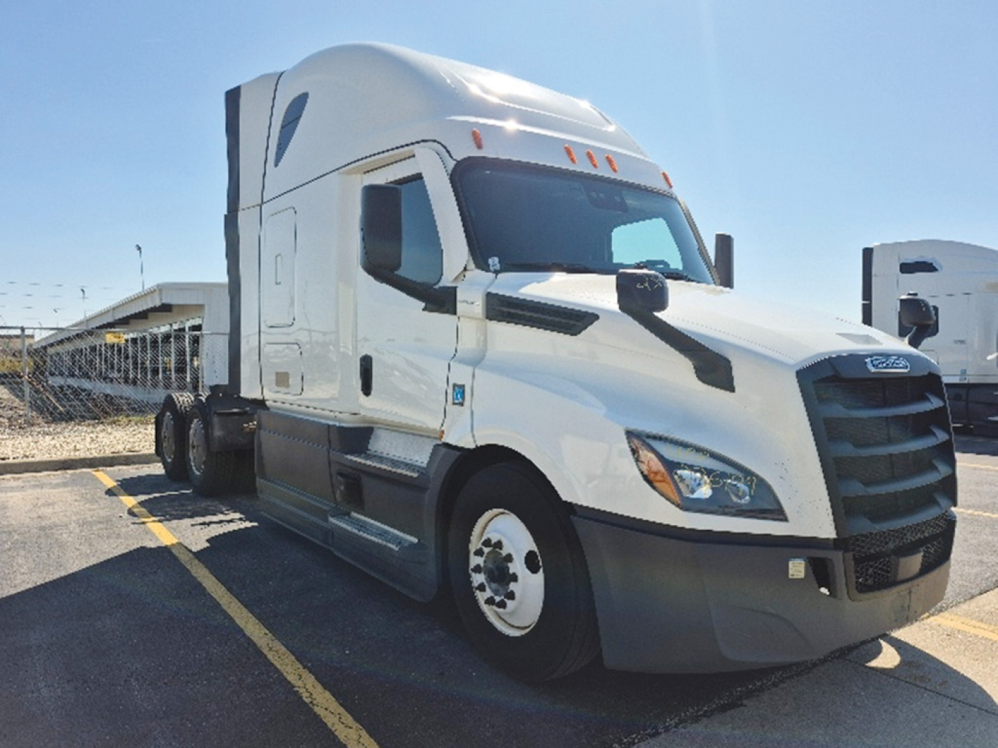 Truck cab exterior showing Freightliner Cascadia sleeper tractor with white paint and black grille