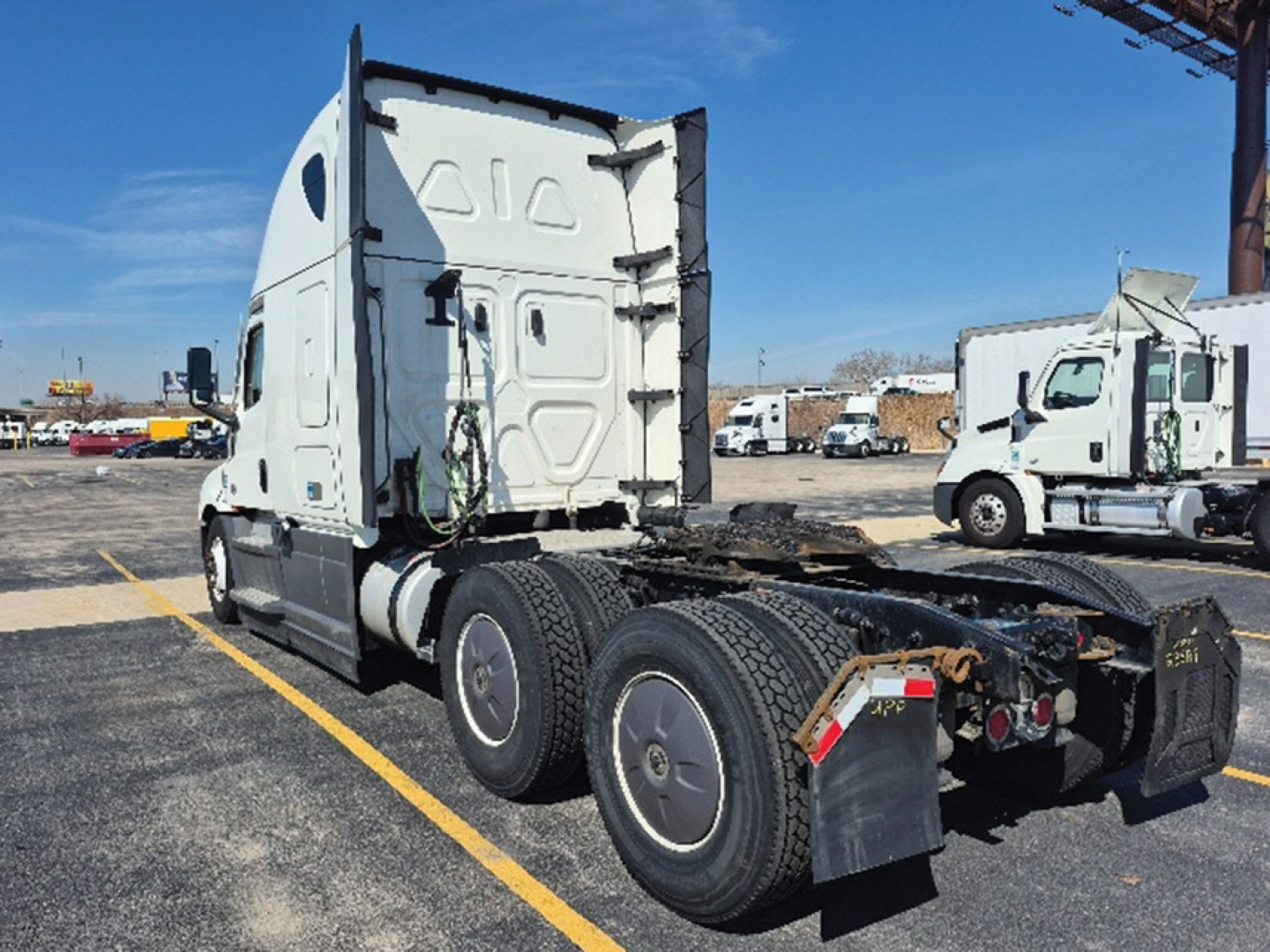 Freightliner Cascadia126 truck tractor cab and rear chassis view with twin rear axles and sleeper cab, white exterior, parked in lot.
