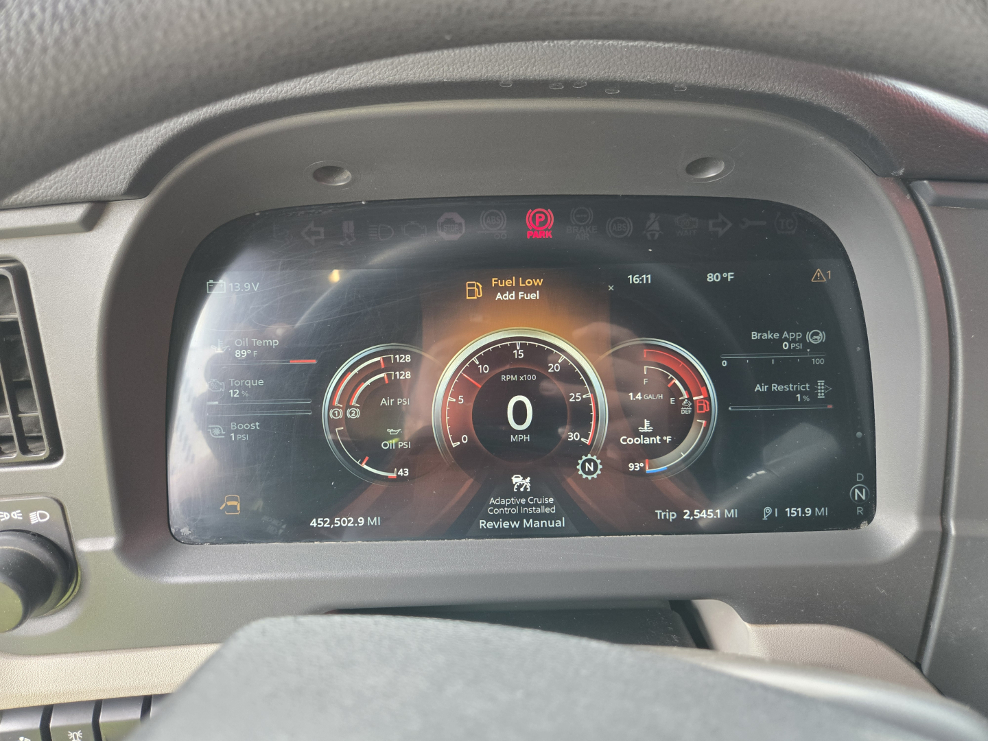 Peterbilt 579 instrument cluster showing digital gauges and warnings: fuel low, brake, coolant, and other indicators; center display with 0 MPH and trip data.