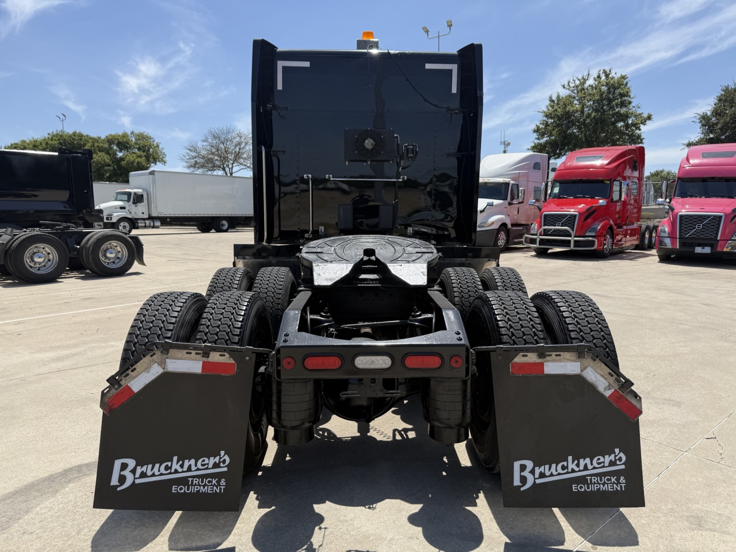 Peterbilt 579 tractor rear view showing dual rear axles, mud flaps reading Bruchner's Truck & Equipment, and fifth wheel with back of cab visible.
