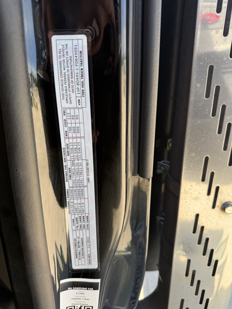 Vehicle placard sticker on a Peterbilt 579 door jamb showing model year and spec details. Text is vertical and dense with small font.