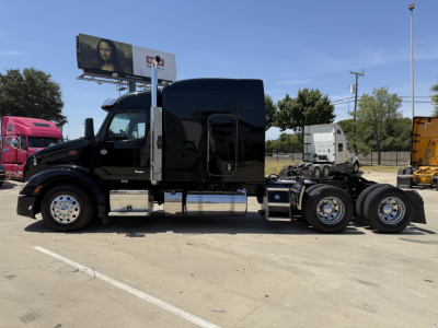 Peterbilt 579 semi-truck tractor in black, side view showing sleeper cab and rear axles with chrome wheels.