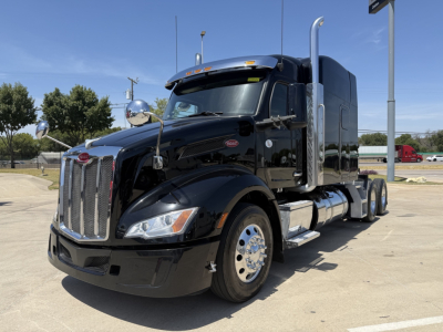Peterbilt 579 conventional sleeper truck in black, front-left view, with chrome grille, dual exhaust stacks, large side fuel tanks, and chrome accents.