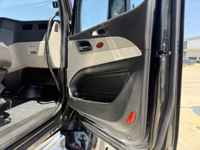 Peterbilt 579 truck interior door panel view showing beige and black interior with door pocket, window switch, and red reflectors.