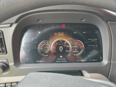 Peterbilt 579 instrument cluster showing digital gauges and warnings: fuel low, brake, coolant, and other indicators; center display with 0 MPH and trip data.