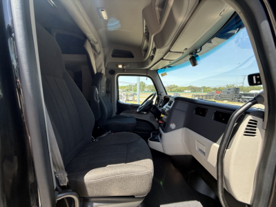 Peterbilt 579 truck cab interior view from passenger side showing dashboard, steering wheel, seats, and door panels.