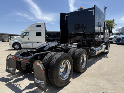 Peterbilt 579 tractor, black sleeper cab, tri-axle rear with chrome wheels, diesel truck in a parking lot.