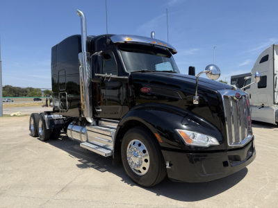 Peterbilt 579 truck side view showing black cab and chrome exhaust stacks with large front grille and dual rear axles.