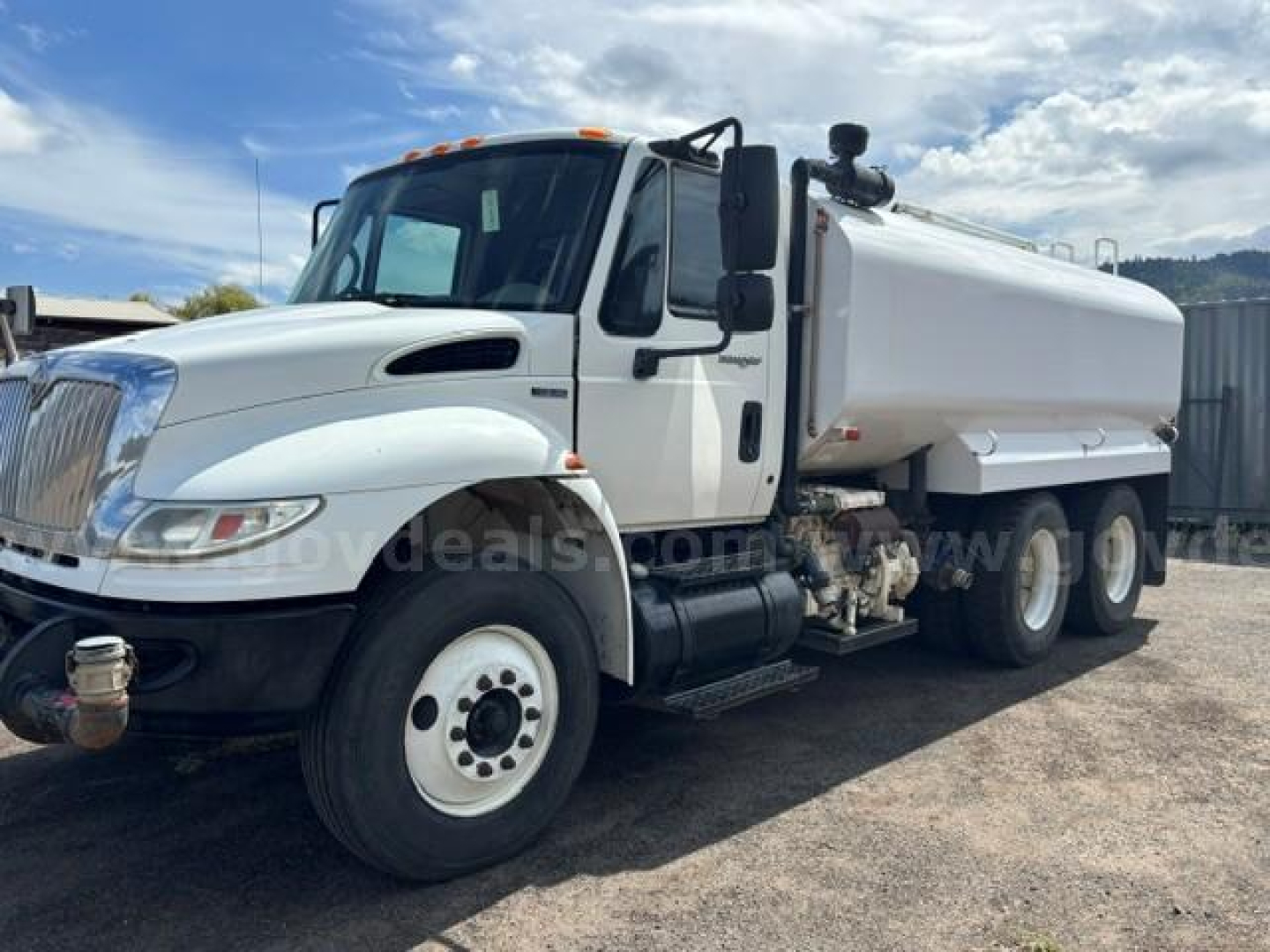 White 2010 International 4400 dump truck in-use with a tank body, side view showing front wheel and dual rear axle, VIN 1HTMSAAR0AH261763 on listing.
