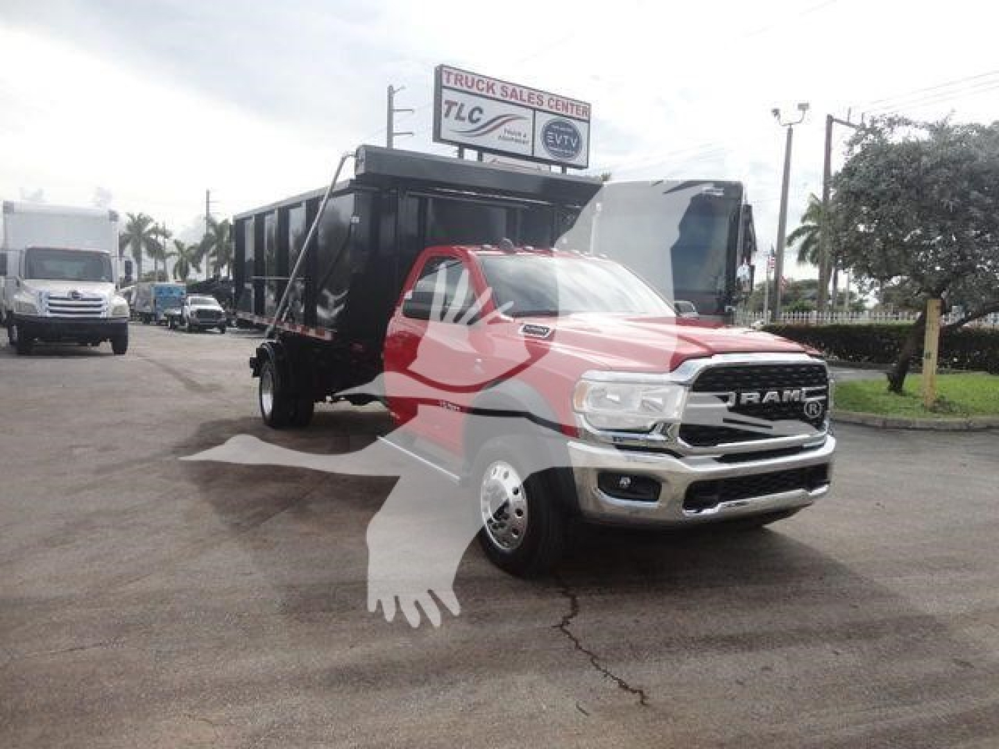 Ram 5500 tow truck with a dump trailer in a lot, front three-quarter view, 2024 Ram 5500 SLT model badge visible on grille.