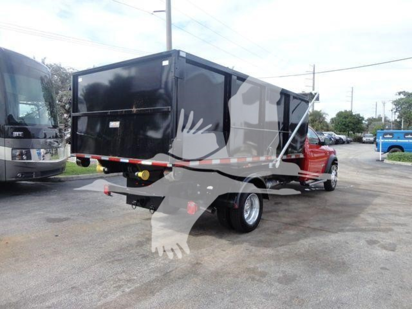 Truck bed showing a large black stake/dump style dump box mounted on a red Ram 5500 SLT chassis with dual rear wheels and rear hitch.