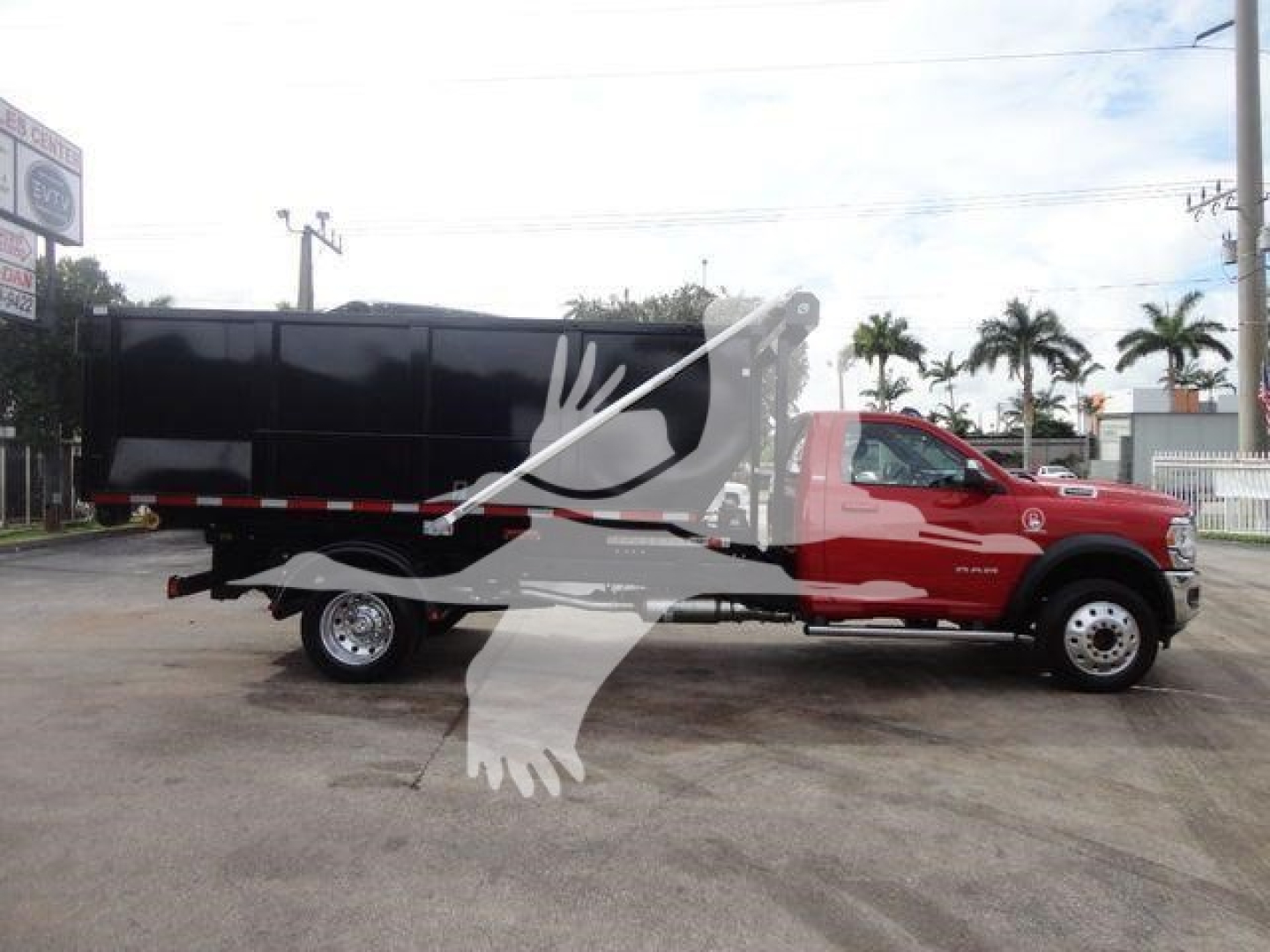 Ram 5500 truck with a black hooklift bed, red cab, side view showing the truck and loading bed.