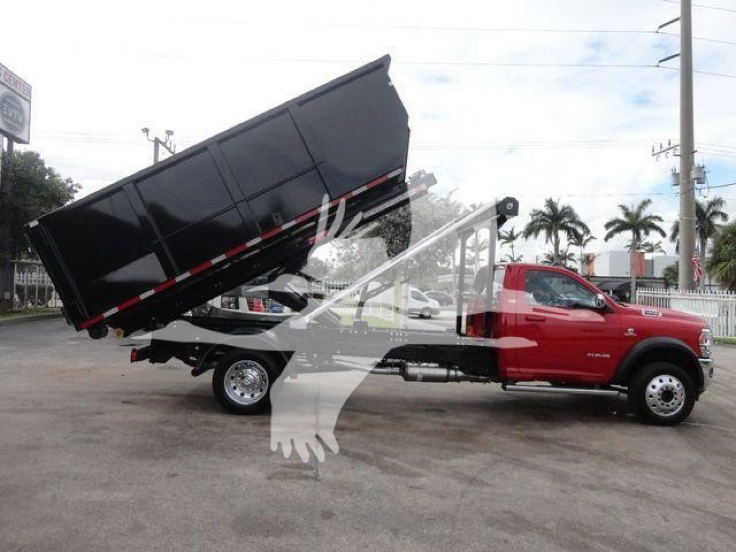 Ram 5500 SLT dump truck with lifted bed, red cab, black dump body in a parking lot.