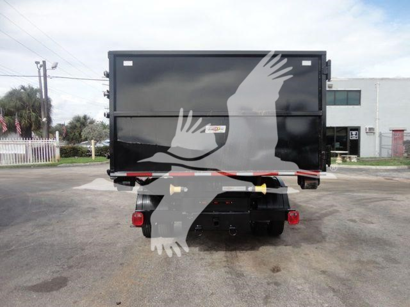 Truck bed rear view showing black hooklift dump body with red taillights and bumper, stock image from rear.