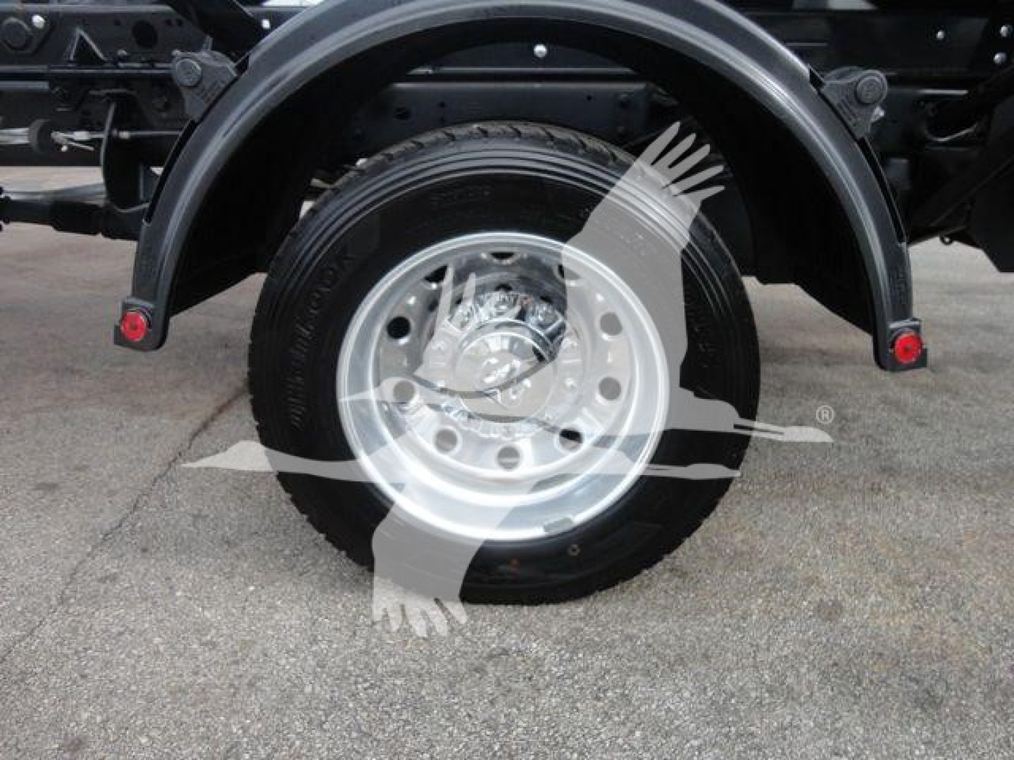 Truck rear wheel and fender showing wheel and tire on Ram 5500 SLT, with exhaust/underbody components visible.