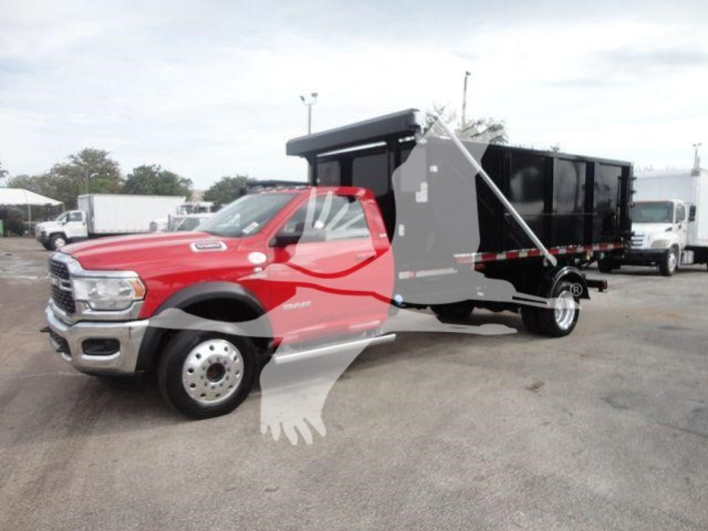 RAM 5500 cab with black dump/box body in a truck lot, red cab, hooklift configuration, side view showing front grille and dual rear wheels.