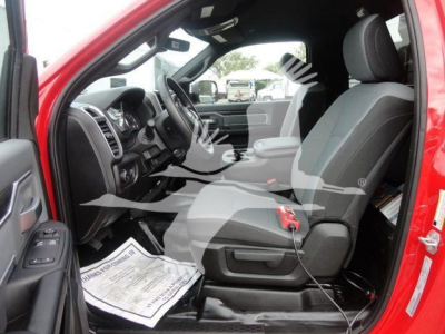 Interior of a red Ram 5500 cab showing front seats and dashboard, with a charger plugged into the 12V/USB area; steering wheel and center console visible.