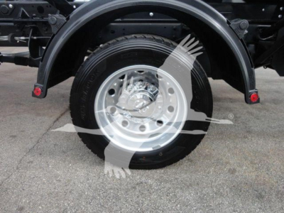 Truck rear wheel and fender showing wheel and tire on Ram 5500 SLT, with exhaust/underbody components visible.