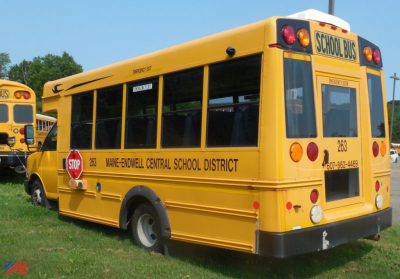 Rear and side view of a yellow 2016 Chevrolet Express micro bus used by Mane-Endwell Central School District with 'SCHOOL BUS' sign, stop sign, and district lettering.