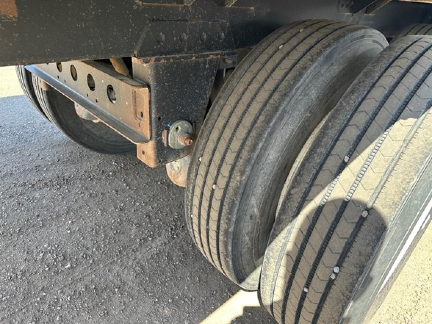Tandem axle trailer wheel area with suspension and mounting bracket visible.