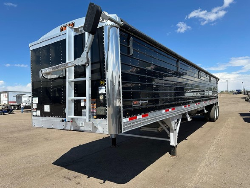 Timpte Super Hopper trailer side and rear view showing black aluminum hopper with silver framing, rear hydraulic door, trailer legs, and reflective striping.