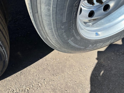 Tire and wheel of trailer showing tire sidewall with markings; part of alloy wheel and hub visible.