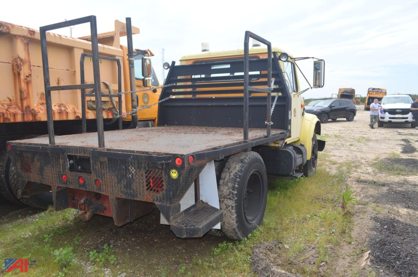 Rear view of a 1994 International 4600 stake bed truck showing flatbed with side rails and dual rear wheels in a used lot.