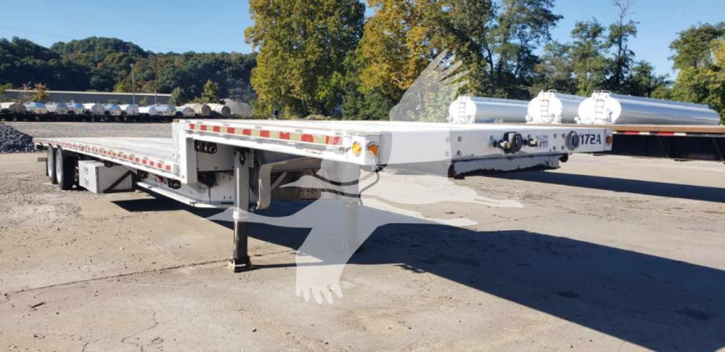 Manac aluminum dropdeck trailer in view showing front area and lowered landing gear with reflective tape along sides.