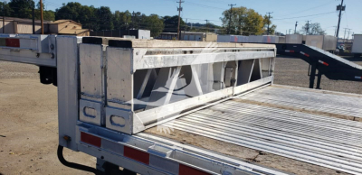 Manac aluminum dropdeck trailer side rear showing open flatbed and tailgate area with aluminum loading ramp in background.