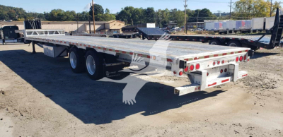 Manac aluminum dropdeck trailer viewed from rear-left side showing tandem axles and rear deck with lighting and reflective tape