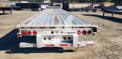 Manac aluminum dropdeck trailer rear view showing multiple red taillights and reflective tape along back edge.