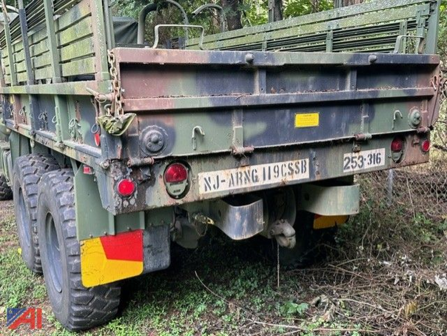 Military cargo truck rear view showing green M923AZ with trailer bed, bumper, tail lights, and license plate NJ- ARNG 119CSSB.