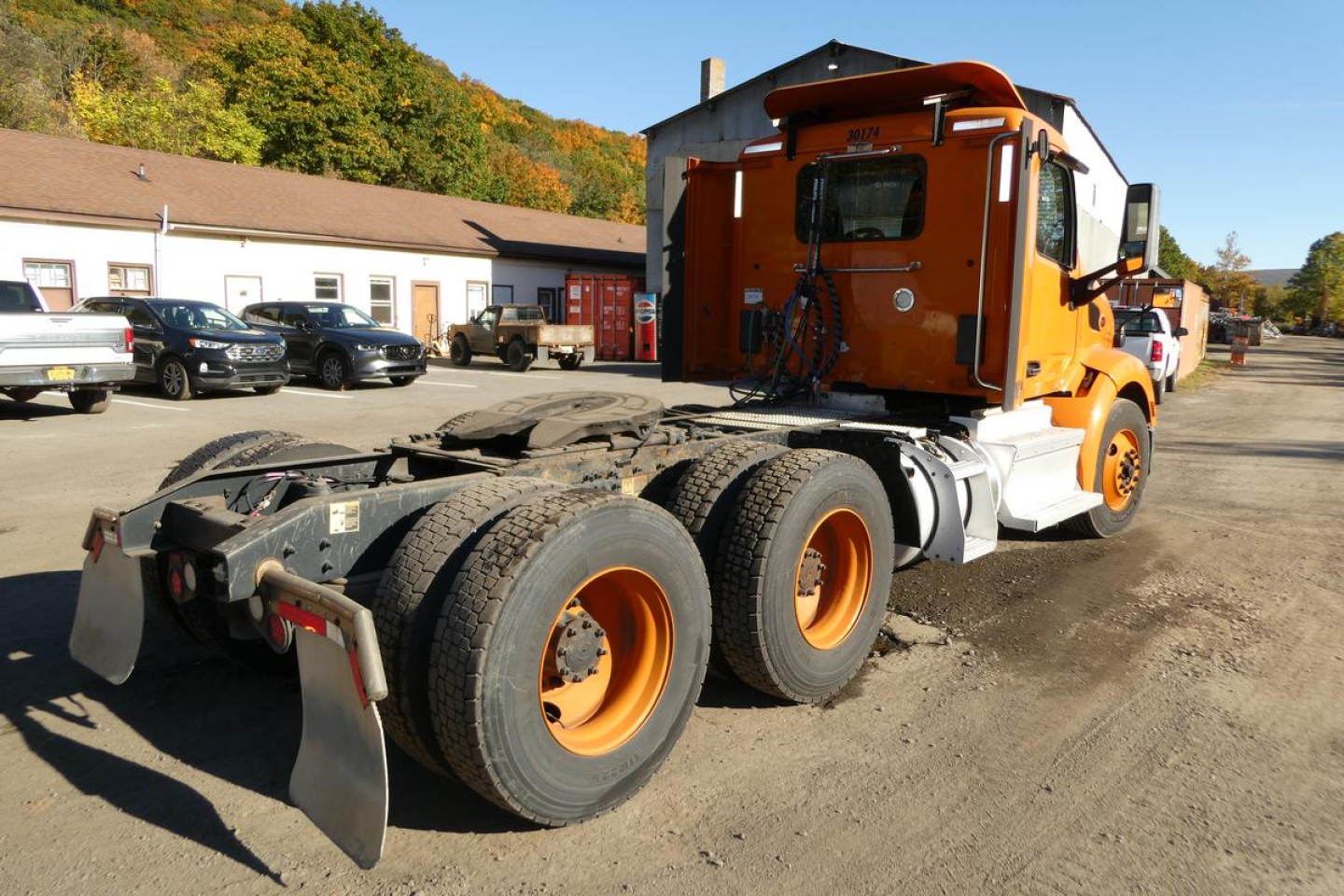 Peterbilt 579 conventional sleeper truck rear view showing fifth wheel and dual rear axles with orange rims.