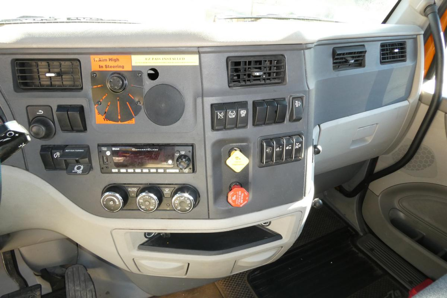 Peterbilt 579 truck interior dashboard view showing gauges, vents, control switches, and orange warning label.