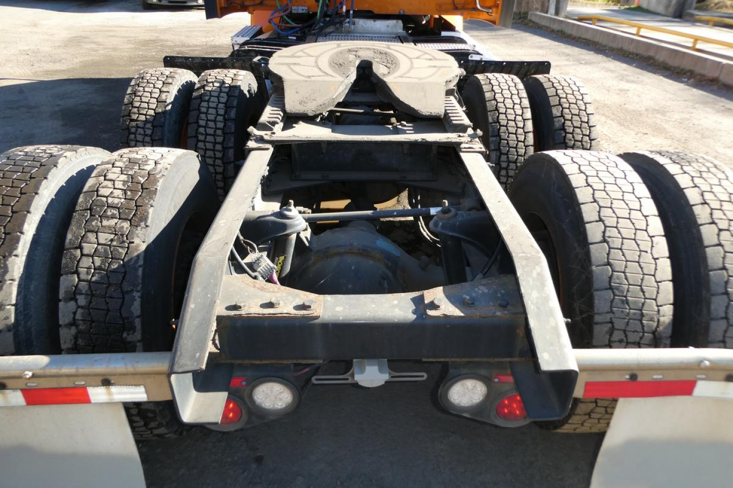 Peterbilt truck chassis rear view showing fifth wheel, suspension, drive axles and dual rear tires.