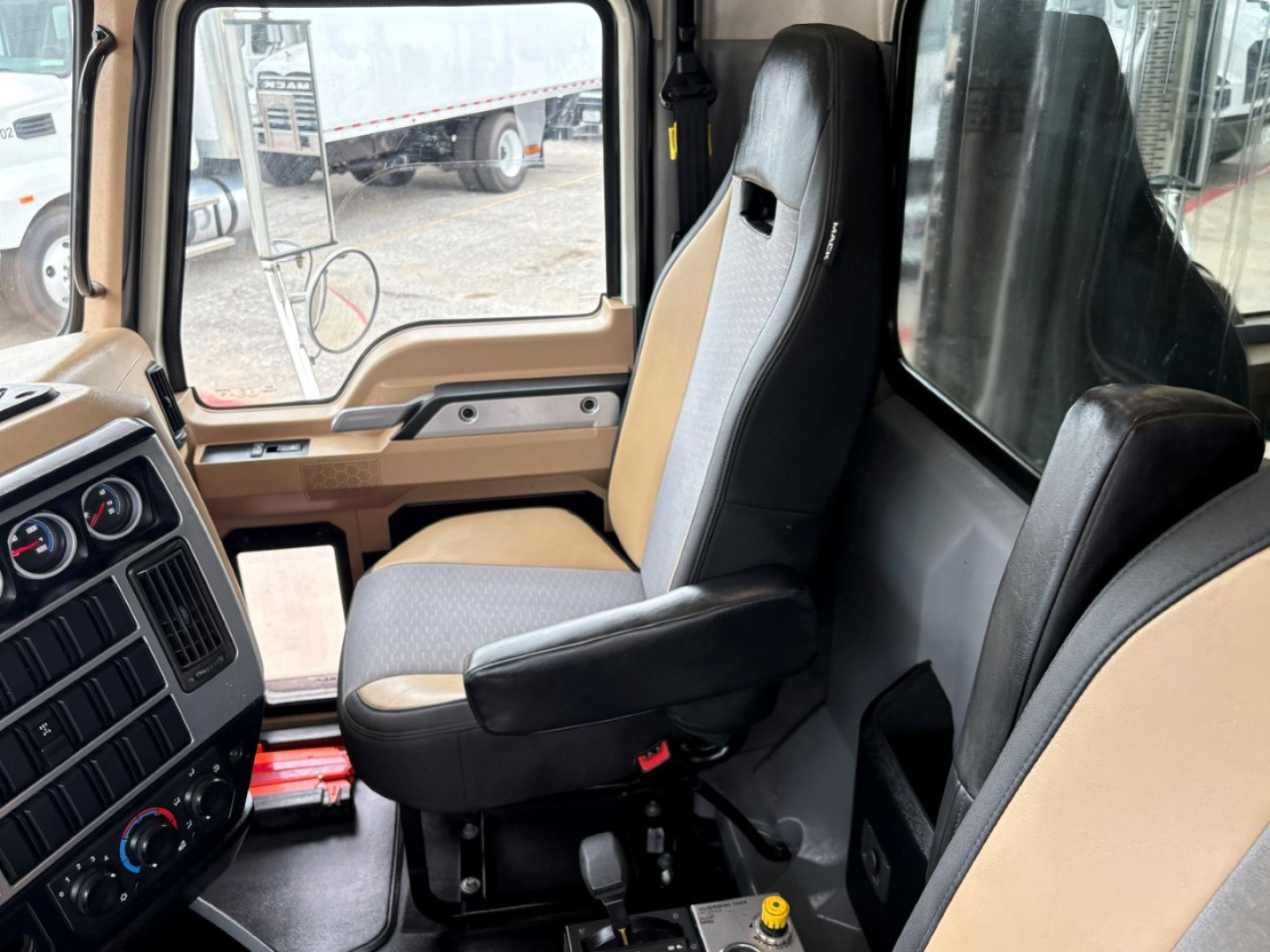 Cab interior of a 2020 Mack GR64F dump truck showing driver seat and passenger seat, steering wheel area, and dashboard with gauges.