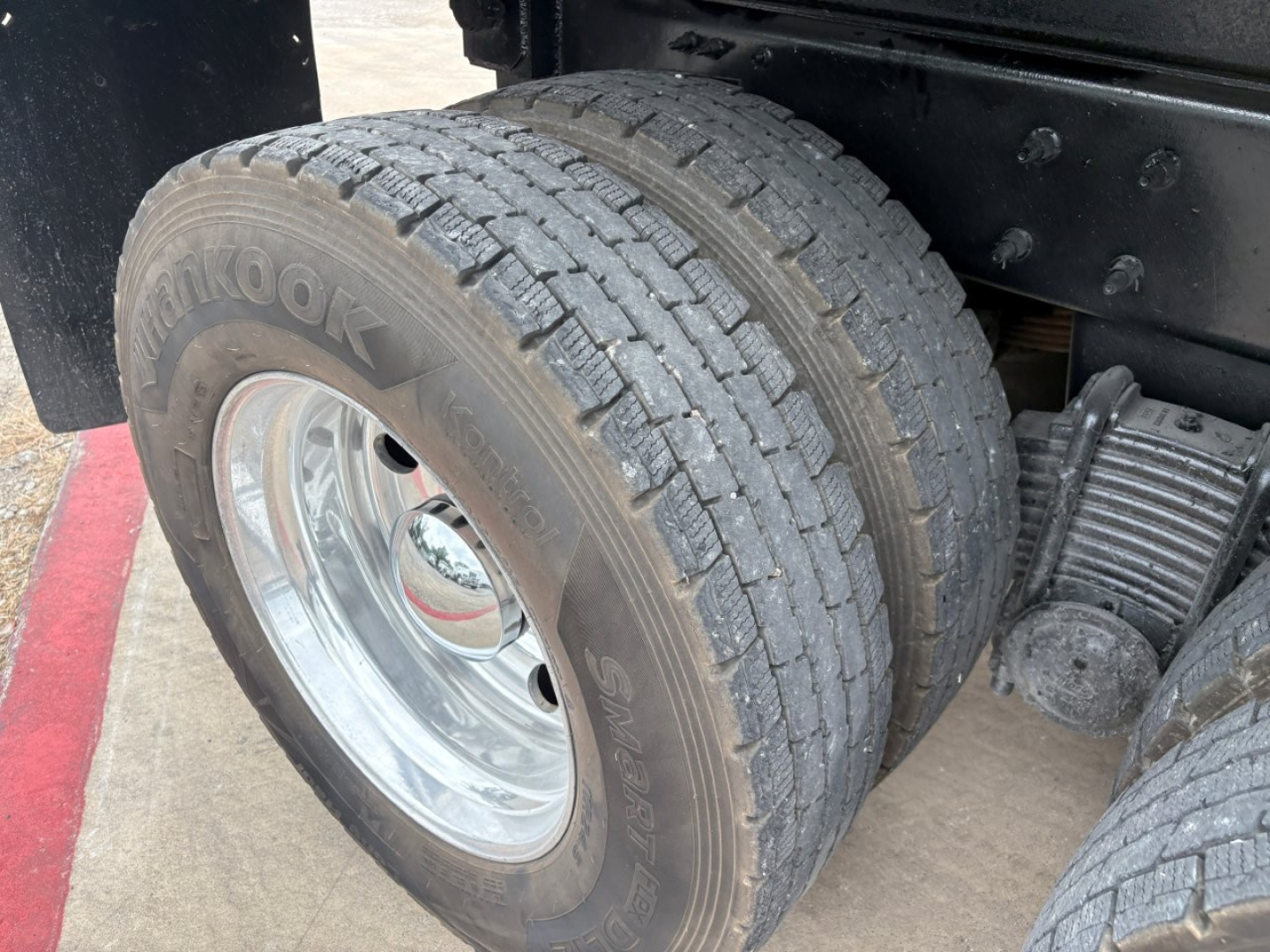 Front dual rear wheel showing Hankook tire and chrome wheel on Mack GR64F dump truck chassis with suspension and driveline components visible.