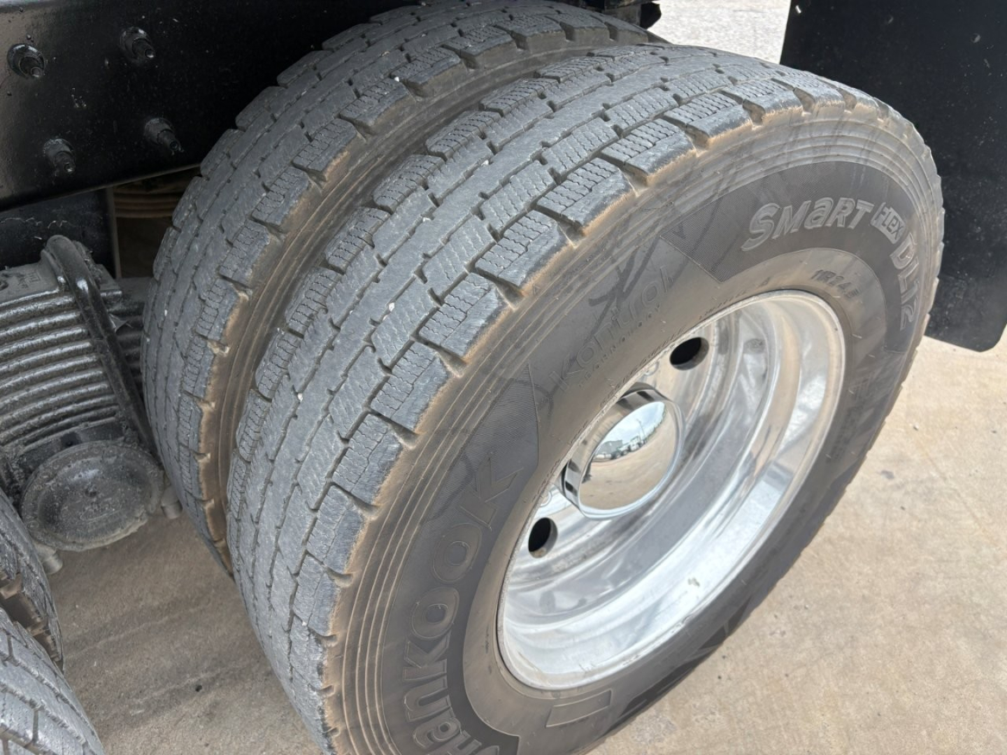 Wheel and tire close-up on a Mack GR64F dump truck showing Goodyear tire and polished steel wheel, partial suspension components visible.
