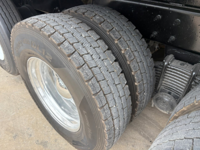 Truck rear dual tires and suspension showing dual rear wheels and leaf spring; tire tread and rim visible.