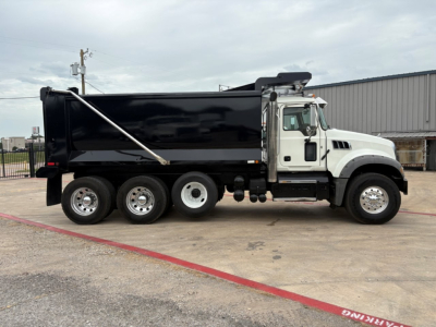 Dump truck side view showing 2020 Mack GR64F with black dump bed and white cab, six wheels, and hydraulic bed cover.