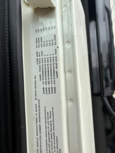 Vehicle label on a Mack GR64F showing GVWR, GAWRs, axle ratings, and tire information with serials and vehicle identification details.