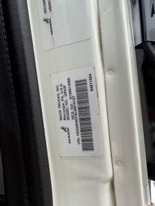 Label on Mack truck door frame showing VIN and model details including 'MACK TRUCKS INC', 'MODEL MD6', 'VIN: 1M2GR4GC6LM016157' and barcode sticker.