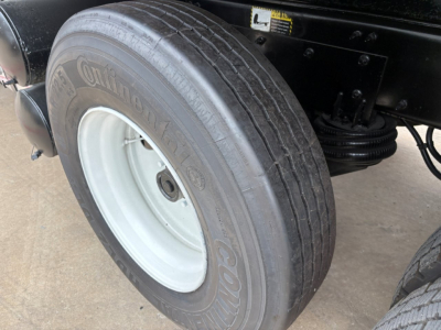 Truck wheel assembly with a Continental tire mounted on a light gray rim and Mack GR64F chassis framing visible in background.