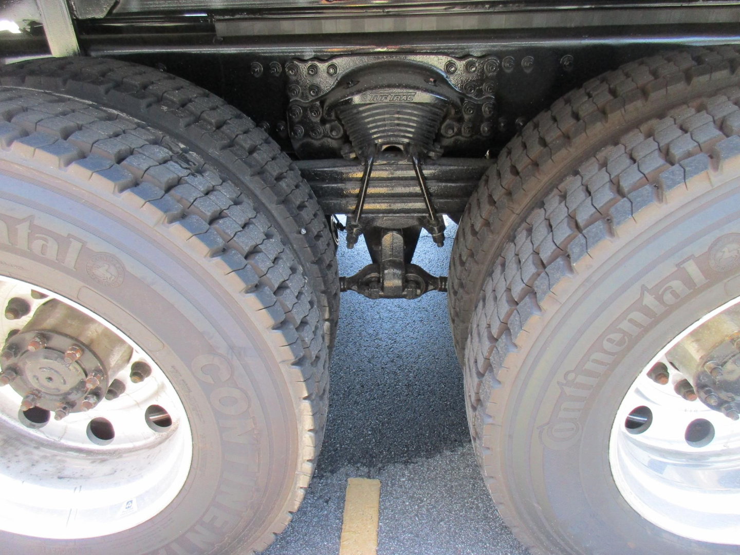 Dual rear wheels and drivetrain view under a Western Star truck showing axles and suspension components.