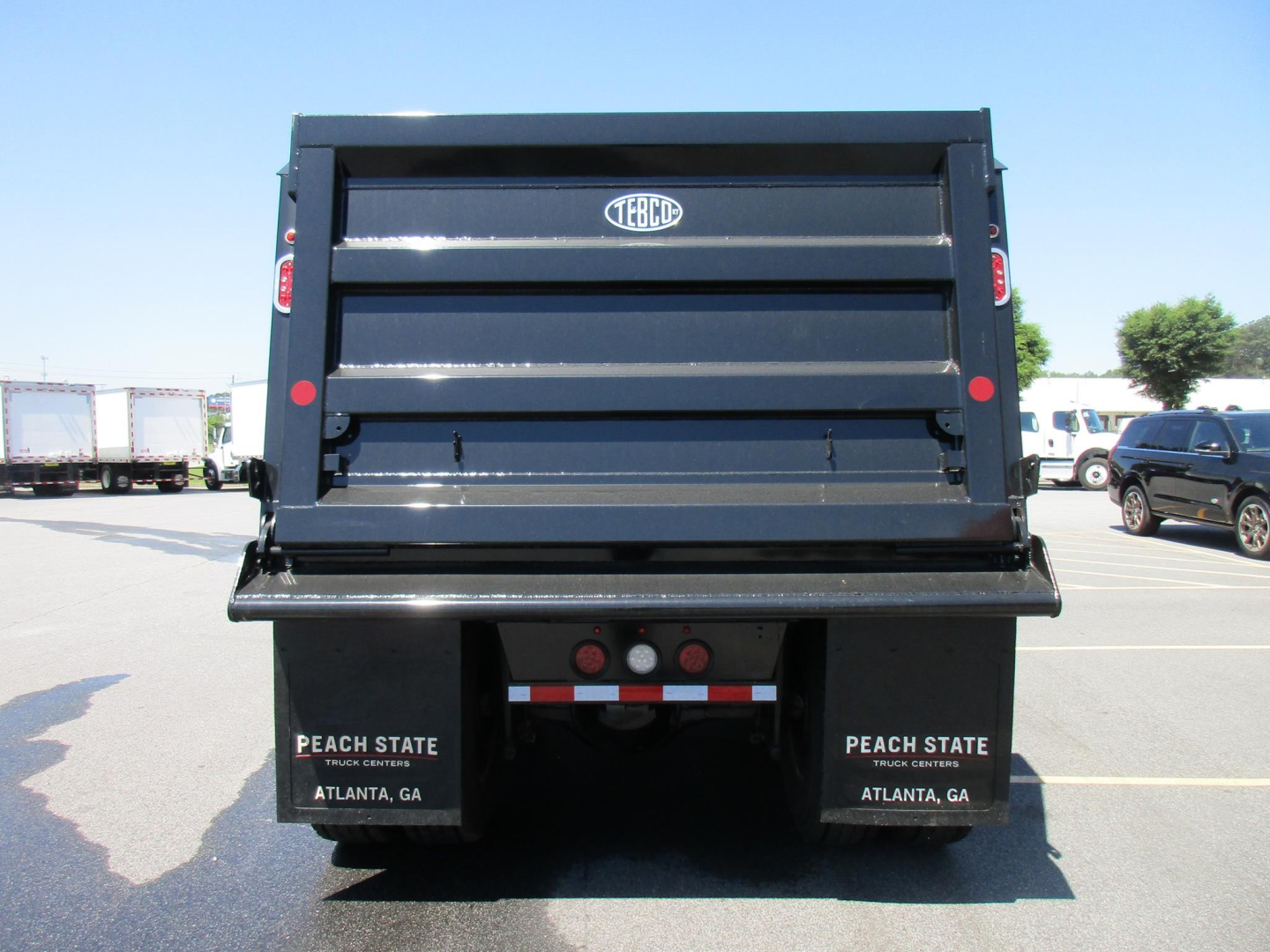 Rear view of a new Western Star dump truck with a TEBCO bed and Peach State plates, showing stock number and city labels.