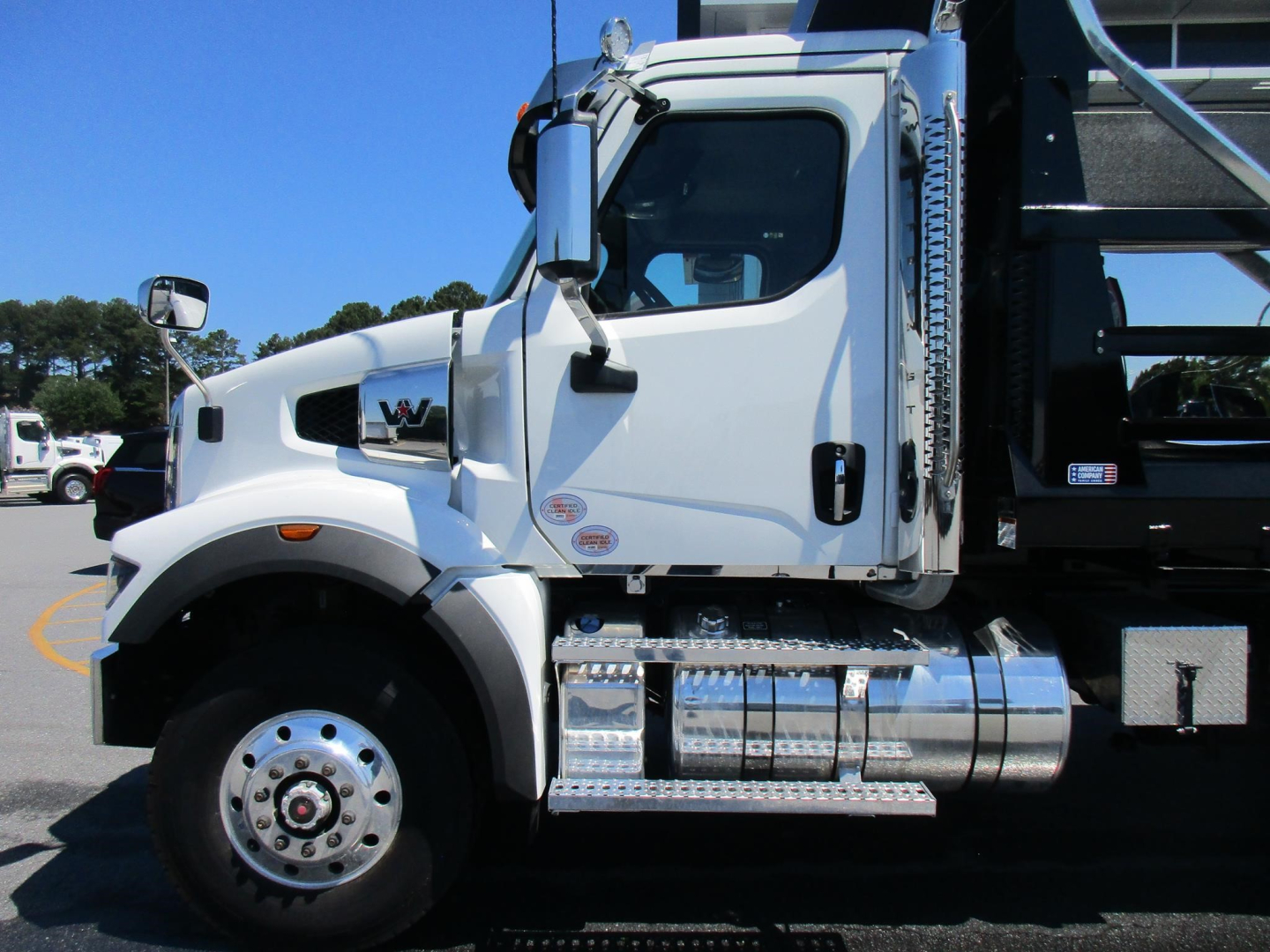 Western Star 47X dump truck side view showing cab and chrome diamond-plate fuel tank with steps.