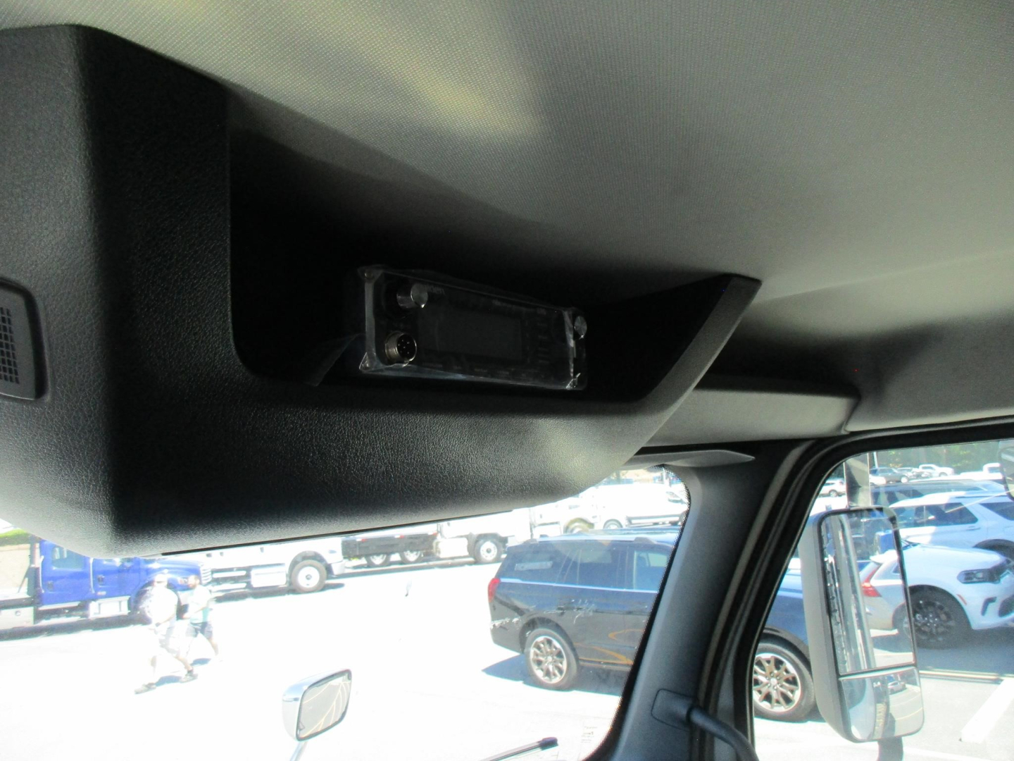 Interior dash area with overhead module and sun visor, small rectangular component mounted inside overhead console in truck cab.