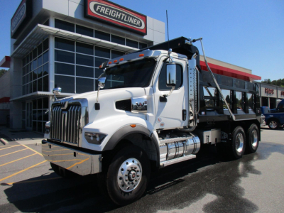 Western Star 47X dump truck in dealership lot, front three-quarter view with chrome grille, dual rear axles, and dump bed.