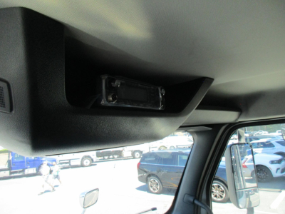 Interior dash area with overhead module and sun visor, small rectangular component mounted inside overhead console in truck cab.