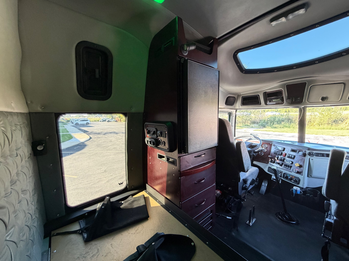 Interior cab area of a 2017 Western Star 5700XE showing driver seat, dashboard, and partition with drawers.